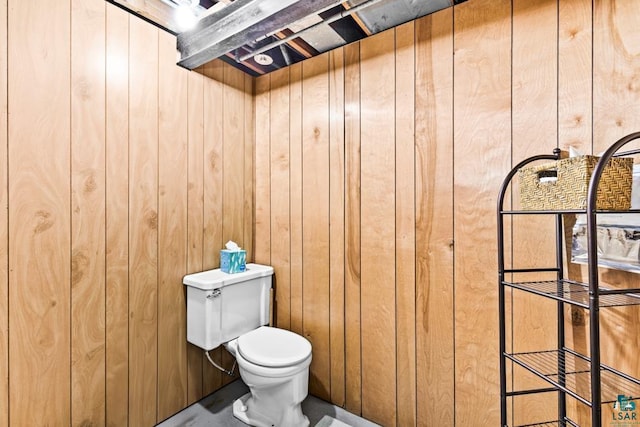 bathroom with toilet and wood walls