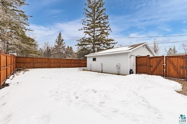 yard layered in snow with a fenced backyard and a gate