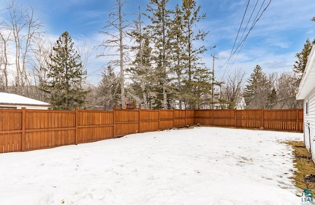 yard covered in snow with a fenced backyard