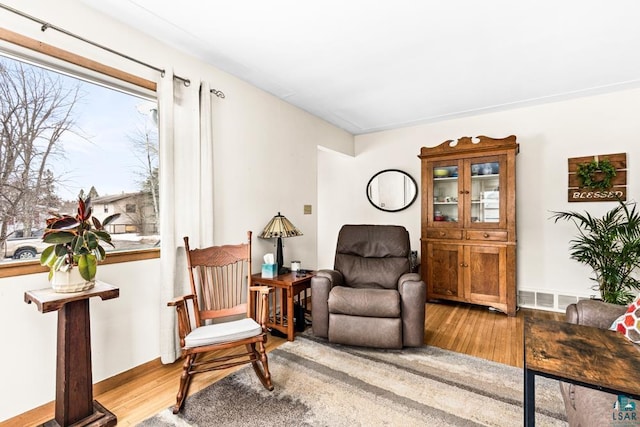 sitting room with wood finished floors, visible vents, and baseboards