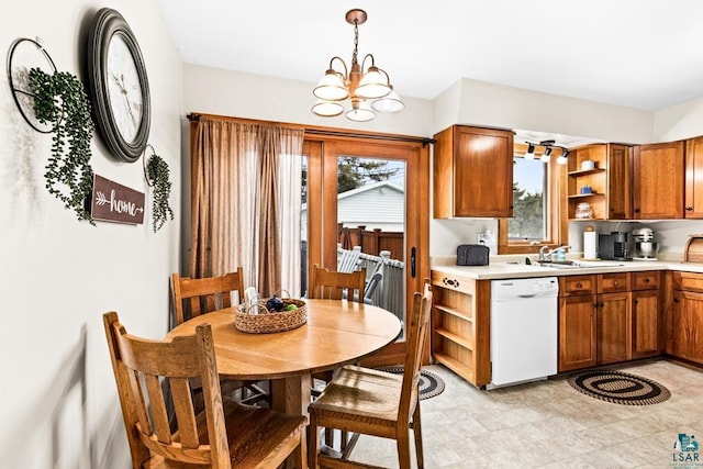 kitchen featuring brown cabinetry, open shelves, white dishwasher, a sink, and a notable chandelier