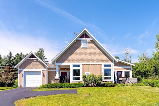 view of front facade featuring a front yard, a garage, and aphalt driveway