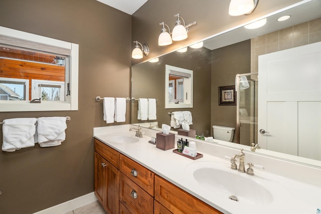 bathroom featuring double vanity, toilet, a stall shower, and a sink