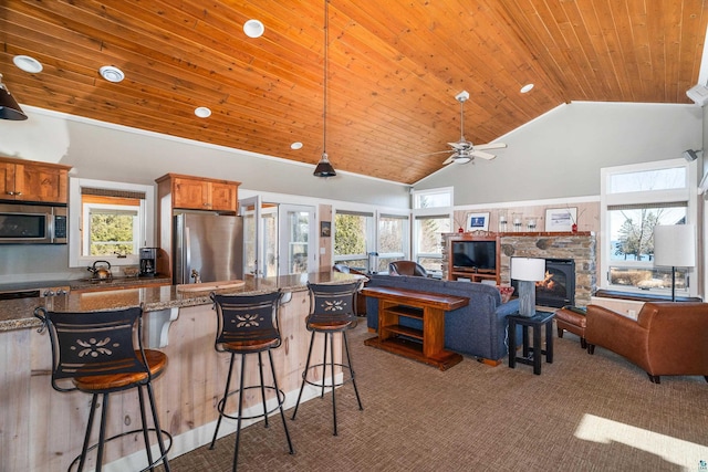 kitchen featuring a breakfast bar, carpet flooring, appliances with stainless steel finishes, wooden ceiling, and high vaulted ceiling