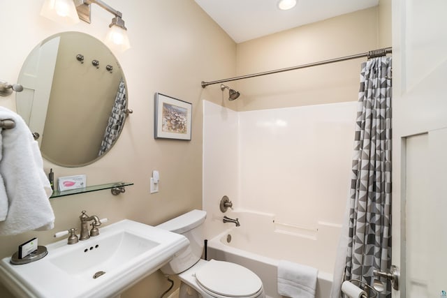 bathroom featuring toilet, shower / bathtub combination with curtain, and a sink