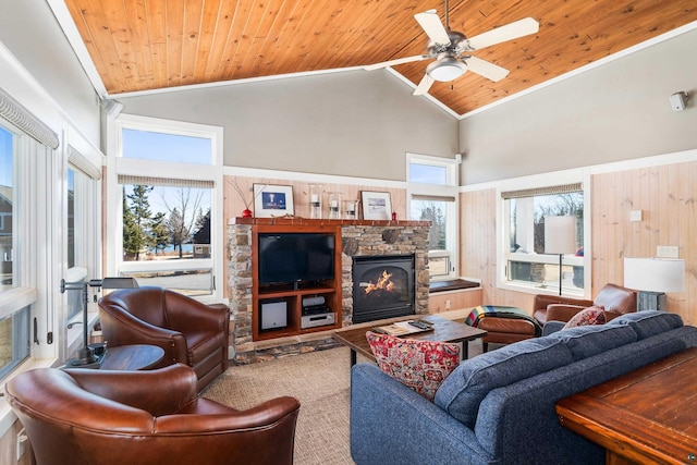 living area featuring a ceiling fan, crown molding, a stone fireplace, and wood ceiling