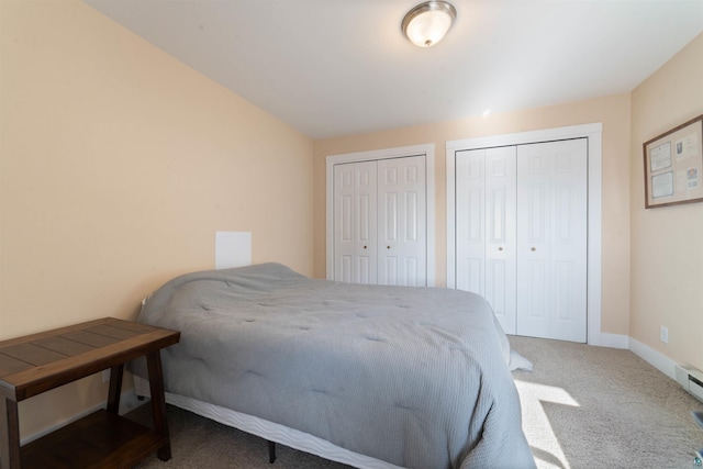 bedroom with baseboards, two closets, and carpet floors