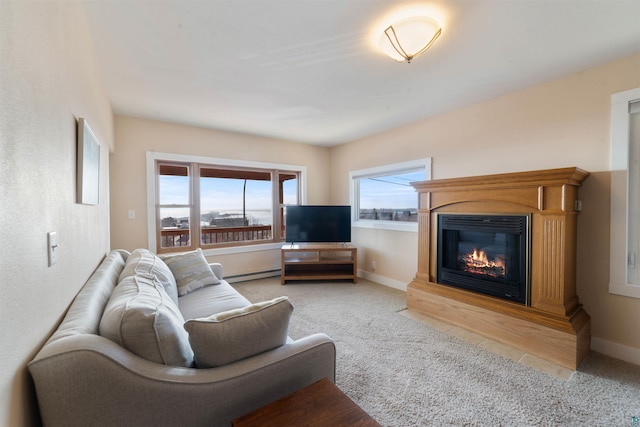 living area featuring a baseboard radiator, light colored carpet, baseboards, and a glass covered fireplace