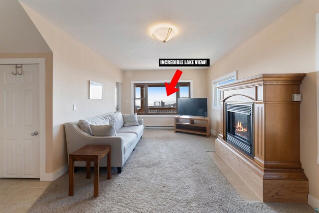 carpeted living area with tile patterned flooring, a glass covered fireplace, baseboards, and a baseboard heating unit