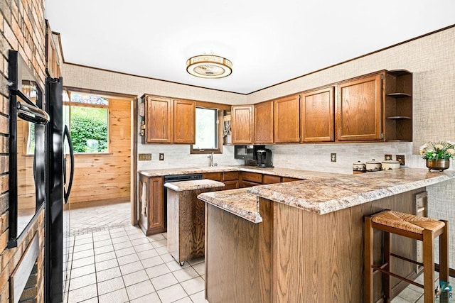kitchen featuring light countertops, open shelves, light tile patterned floors, a peninsula, and brown cabinetry