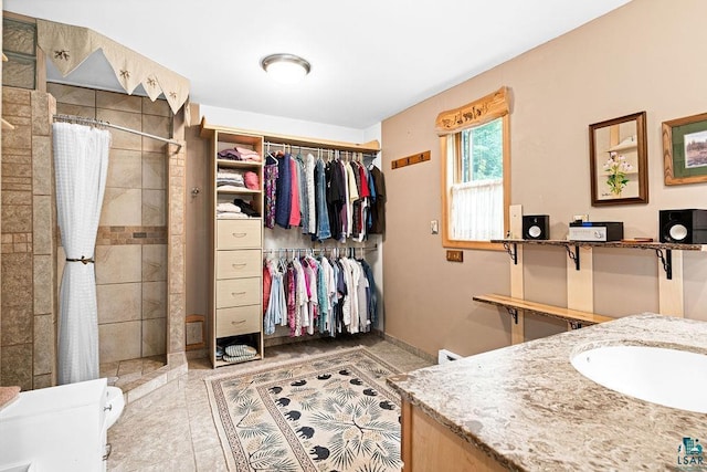 full bath with a spacious closet, tile patterned floors, vanity, and tiled shower