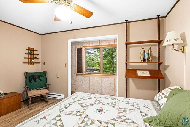 bedroom with ornamental molding, wood finished floors, a baseboard heating unit, and a ceiling fan