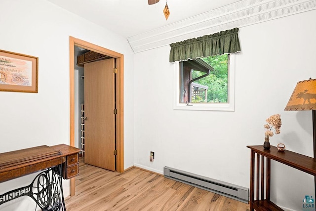 hallway featuring a baseboard radiator, baseboards, and light wood-type flooring