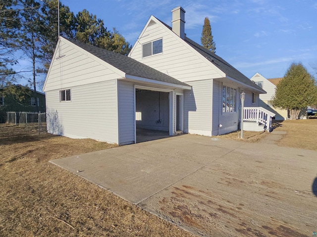 back of house featuring a shingled roof and a chimney