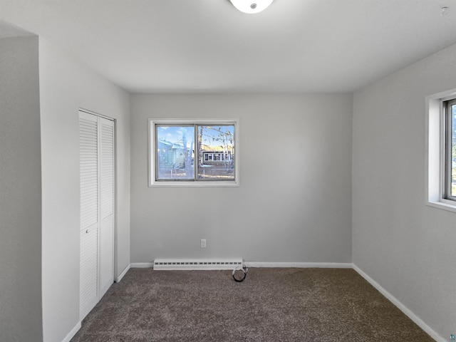 unfurnished bedroom featuring baseboards, carpet floors, a baseboard heating unit, and a closet