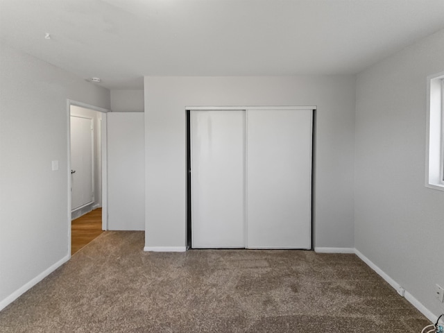 unfurnished bedroom with a closet, carpet flooring, and baseboards