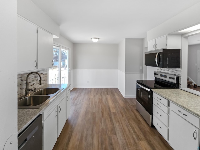 kitchen featuring wainscoting, a sink, black microwave, dishwashing machine, and stainless steel electric stove