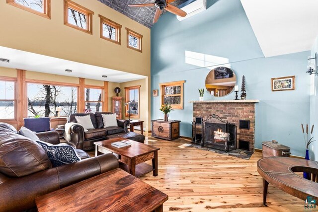 living room featuring baseboards, a ceiling fan, a brick fireplace, and hardwood / wood-style flooring