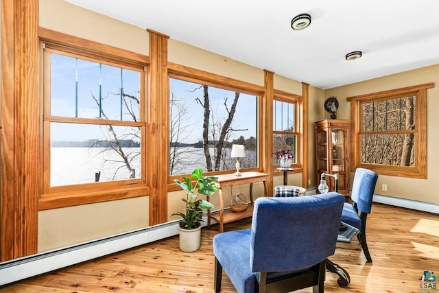 sitting room with a water view, baseboards, hardwood / wood-style floors, and baseboard heating
