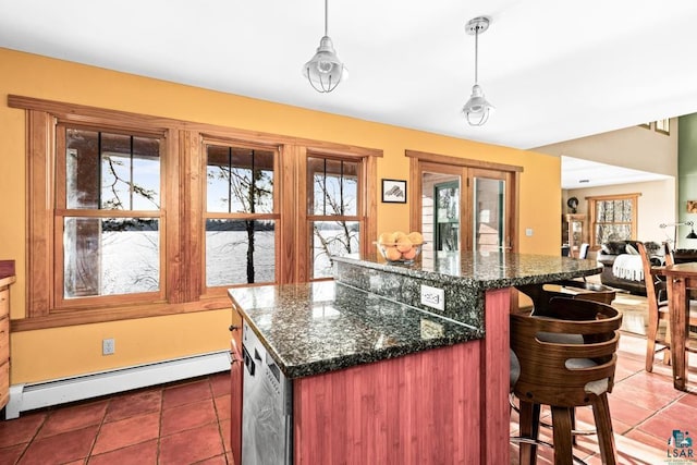 kitchen featuring decorative light fixtures, a baseboard radiator, a kitchen breakfast bar, dark stone counters, and a kitchen island