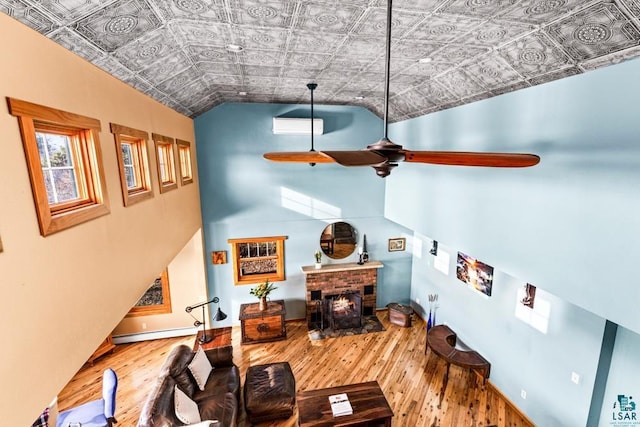 living room featuring baseboard heating, wood finished floors, a ceiling fan, and an ornate ceiling