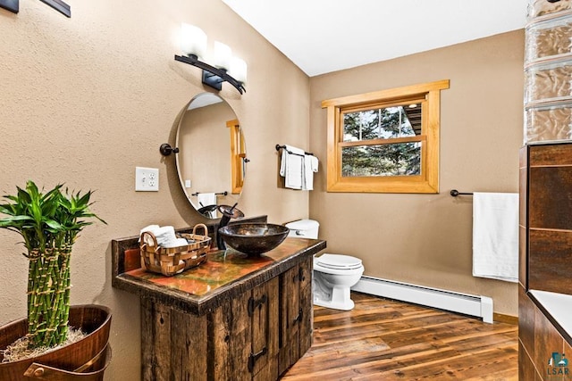 bathroom featuring vanity, baseboards, toilet, a baseboard radiator, and wood finished floors