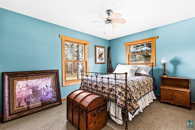 carpeted bedroom featuring a ceiling fan, baseboards, and multiple windows