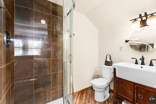 full bathroom with toilet, vanity, wood finished floors, a stall shower, and lofted ceiling