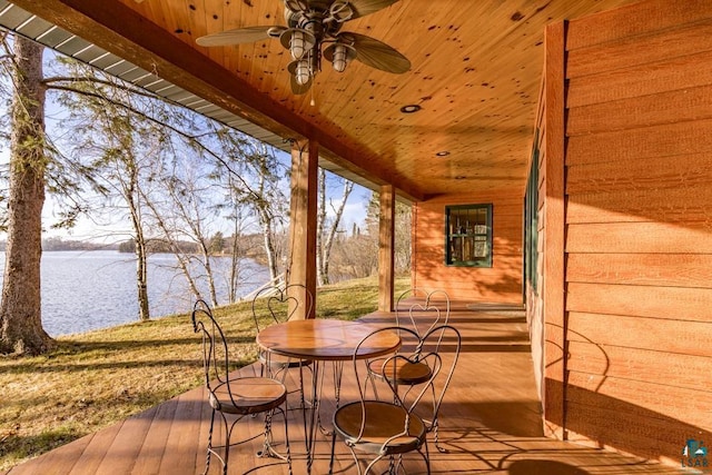 deck featuring ceiling fan, outdoor dining area, and a water view