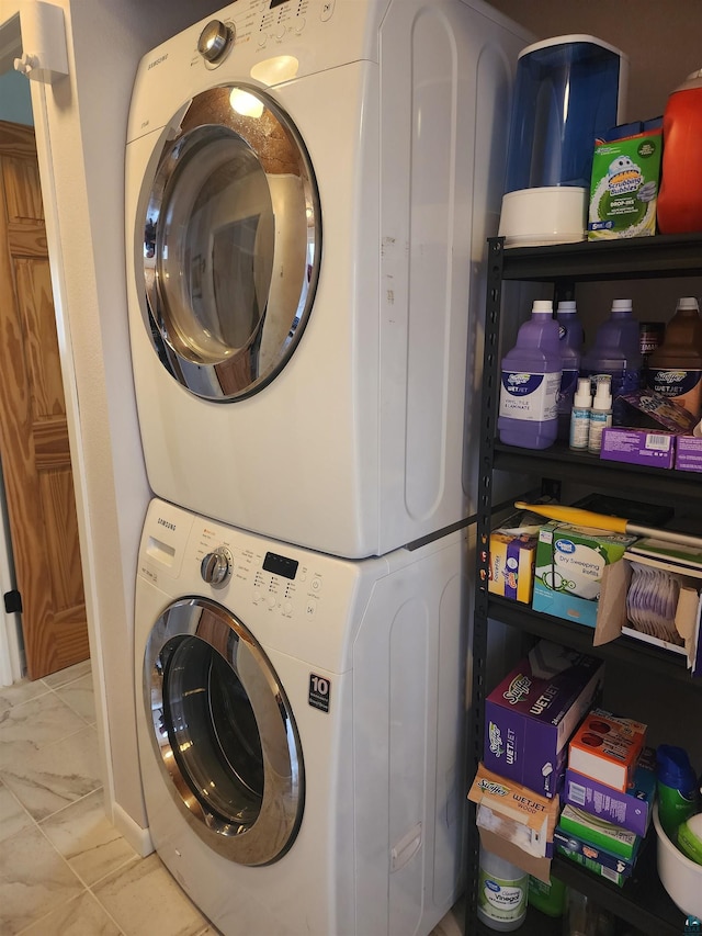 laundry room featuring laundry area, stacked washing maching and dryer, and marble finish floor