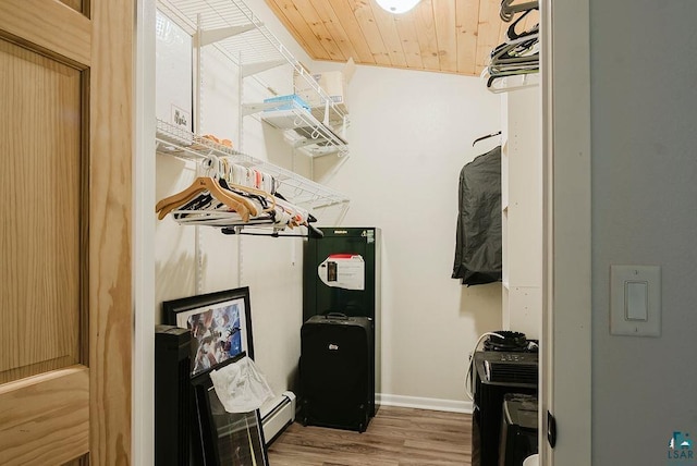 walk in closet with a baseboard heating unit and wood finished floors