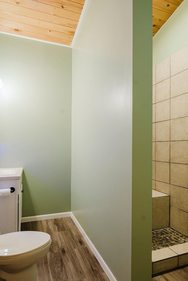 bathroom featuring wood finished floors, toilet, baseboards, tiled shower, and wood ceiling
