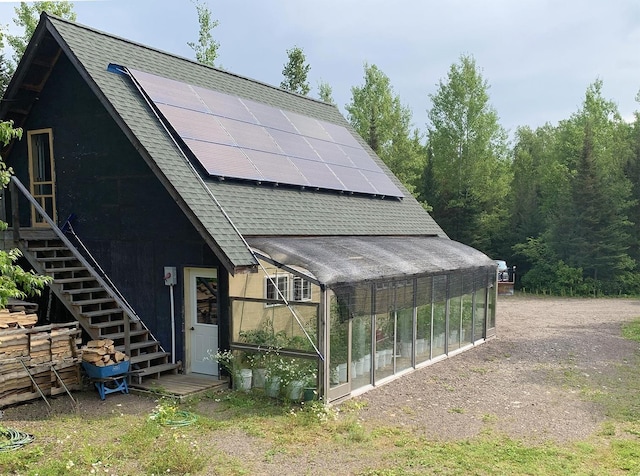 8352 Old Gunflint Trl, Grand Marais, MN 55604 - exterior space with solar panels, an exterior structure, stairway, an outbuilding, and roof with shingles