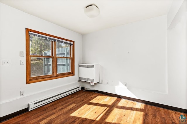 spare room with baseboard heating, wood finished floors, and heating unit