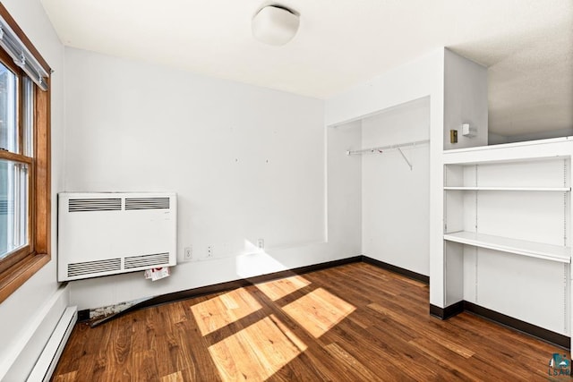 washroom featuring baseboards, a baseboard heating unit, heating unit, a wall unit AC, and wood finished floors