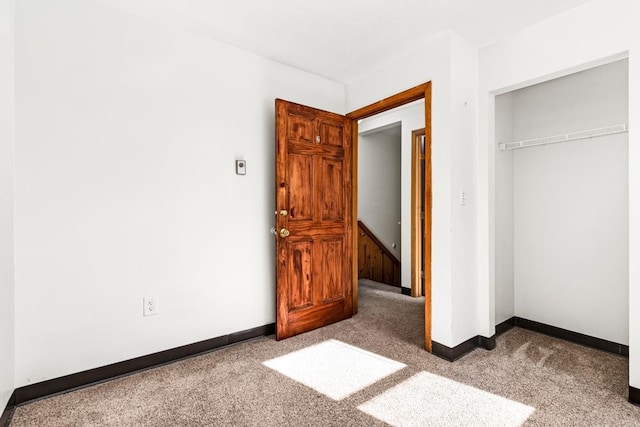 unfurnished bedroom with a closet, baseboards, and carpet flooring