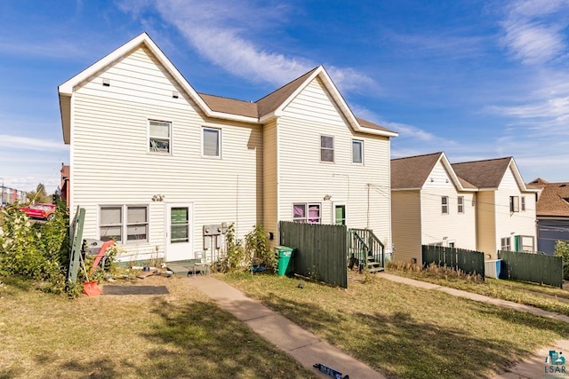 back of house with fence and a lawn