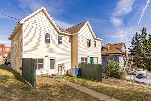 rear view of property with fence and a lawn