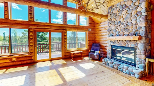 living area featuring high vaulted ceiling, rustic walls, beamed ceiling, a fireplace, and wood-type flooring