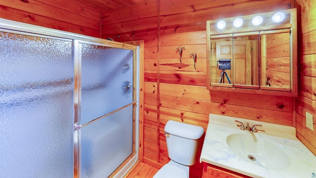 full bathroom featuring a shower stall, toilet, vanity, and wooden walls