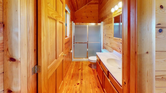 bathroom with lofted ceiling, vanity, wooden walls, and a stall shower
