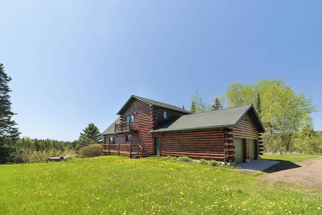 view of side of property with a yard, log exterior, a garage, and a balcony