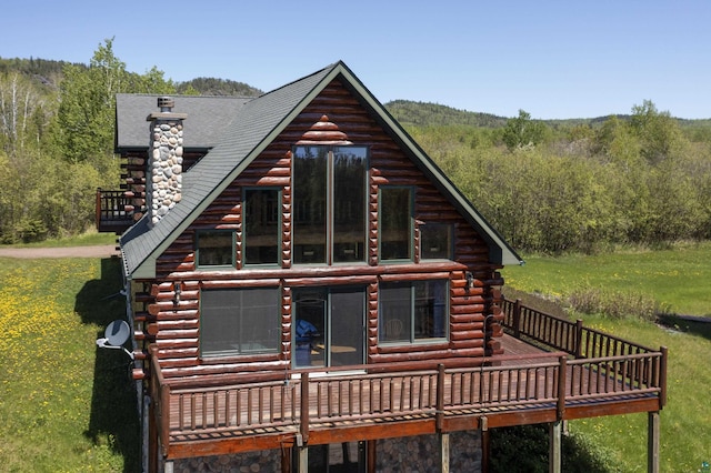 back of property with a yard, a chimney, log siding, and a deck