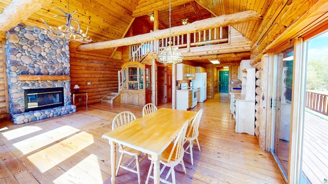 dining area featuring rustic walls, light wood-style flooring, high vaulted ceiling, and a chandelier