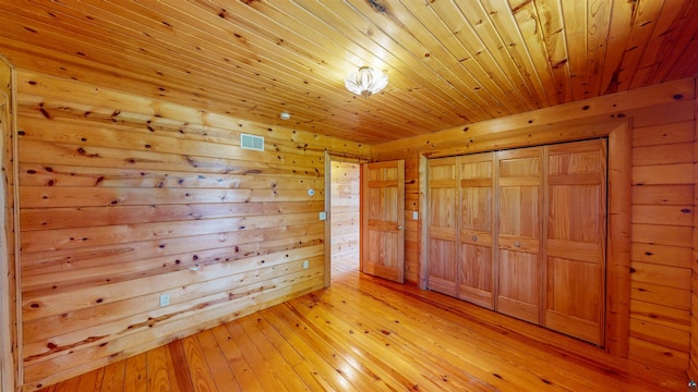 unfurnished bedroom featuring light wood-style flooring, a closet, wood walls, and wood ceiling