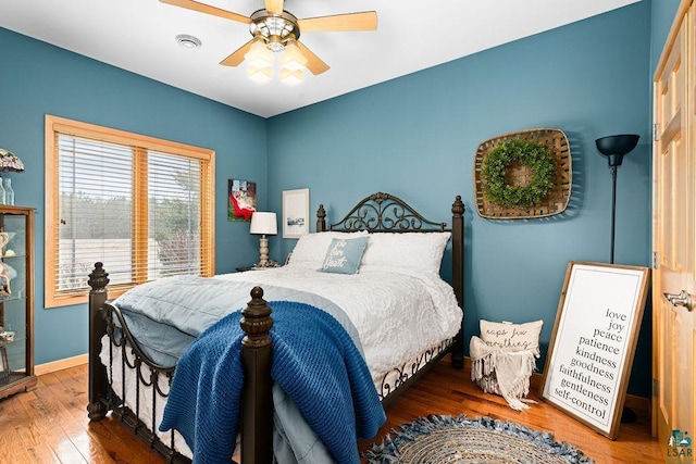 bedroom featuring wood finished floors, visible vents, baseboards, and ceiling fan