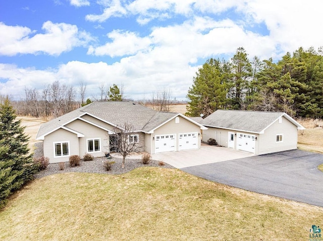 ranch-style home featuring an attached garage, aphalt driveway, and a front yard