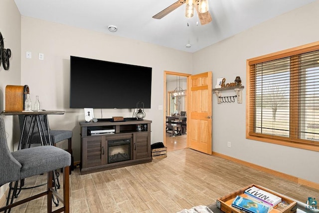 living room with light wood-style floors, baseboards, and ceiling fan