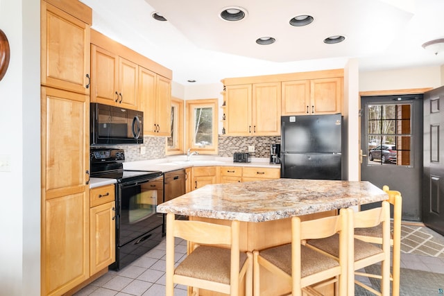 kitchen featuring light tile patterned floors, light countertops, light brown cabinetry, and black appliances