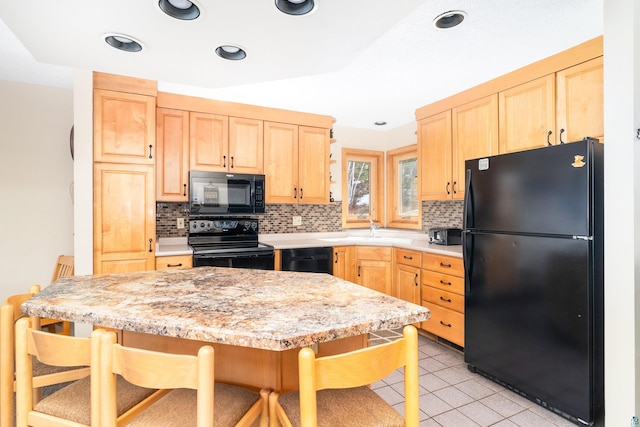 kitchen featuring black appliances, decorative backsplash, light brown cabinetry, and a breakfast bar